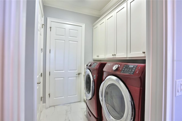 washroom featuring crown molding, washing machine and clothes dryer, and cabinets