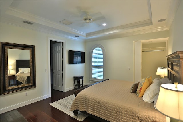 bedroom with crown molding, dark hardwood / wood-style floors, and a raised ceiling