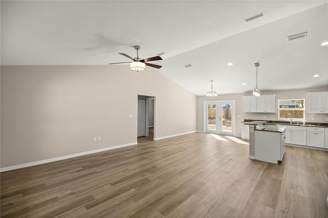 kitchen featuring sink, white cabinetry, light hardwood / wood-style floors, decorative light fixtures, and french doors