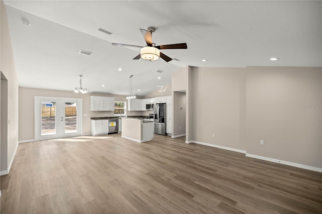 unfurnished living room with vaulted ceiling, ceiling fan with notable chandelier, a textured ceiling, and light hardwood / wood-style flooring