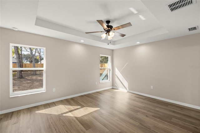 spare room with hardwood / wood-style floors, ceiling fan, and a tray ceiling