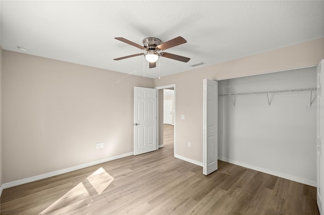 unfurnished bedroom featuring ceiling fan, a closet, and light hardwood / wood-style flooring