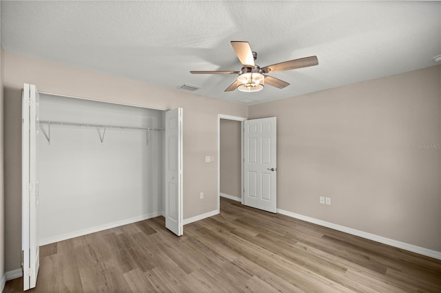 unfurnished bedroom featuring ceiling fan, a textured ceiling, a closet, and light wood-type flooring