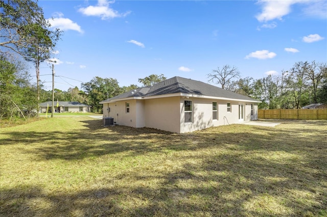 rear view of house with cooling unit, a lawn, and a patio area