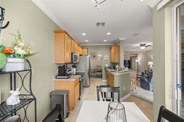 kitchen with light tile patterned floors, ceiling fan, stainless steel appliances, ornamental molding, and kitchen peninsula