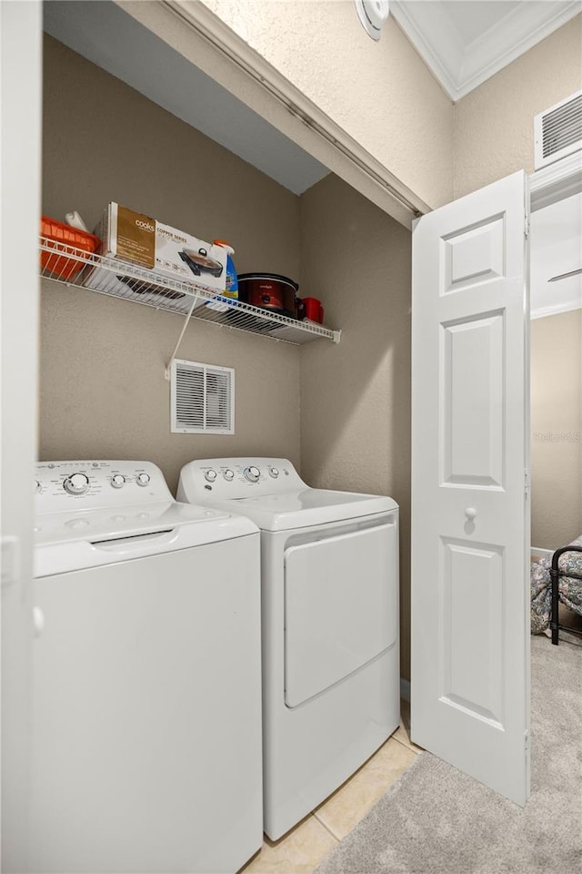 washroom featuring ornamental molding, washing machine and clothes dryer, and light tile patterned flooring