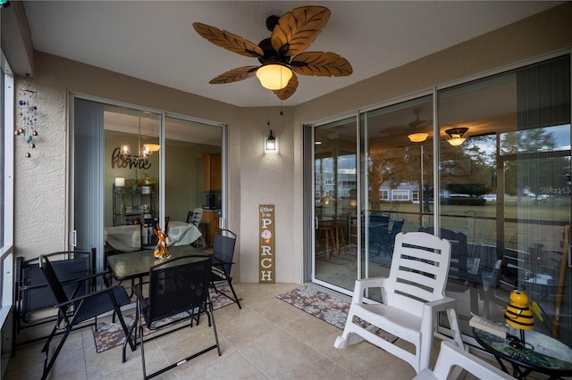 sunroom / solarium featuring ceiling fan with notable chandelier