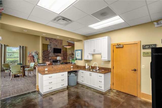 kitchen with black refrigerator, a paneled ceiling, sink, white cabinets, and kitchen peninsula