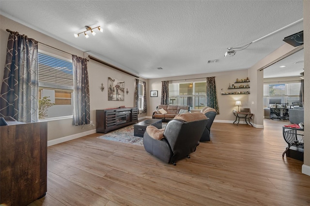 living room with a wealth of natural light, light hardwood / wood-style floors, and a textured ceiling