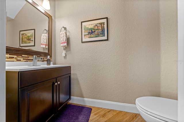 bathroom featuring vanity, hardwood / wood-style flooring, tasteful backsplash, and toilet