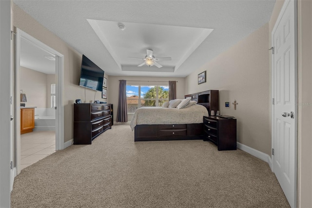 carpeted bedroom featuring ensuite bathroom, a textured ceiling, ceiling fan, and a tray ceiling