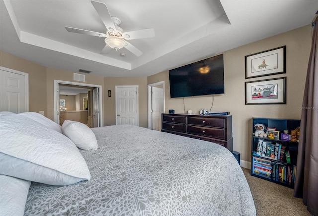 carpeted bedroom featuring a raised ceiling and ceiling fan