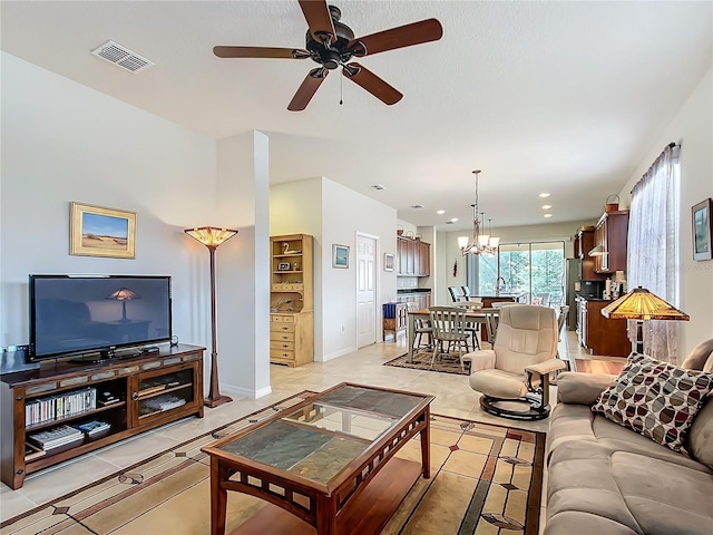 living room with light tile patterned flooring and ceiling fan with notable chandelier