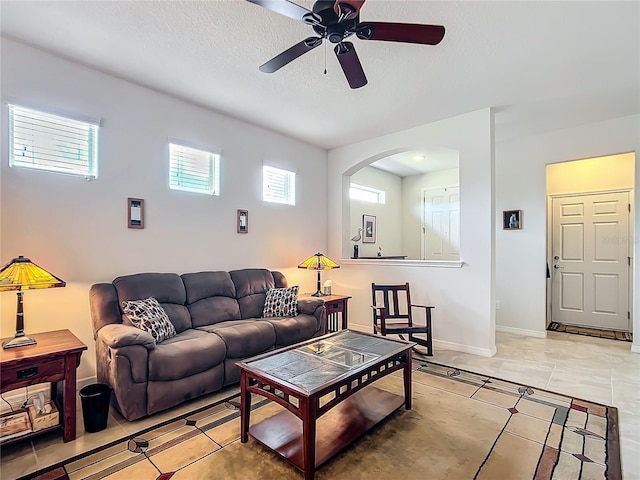 living room featuring tile patterned flooring, ceiling fan, and a textured ceiling