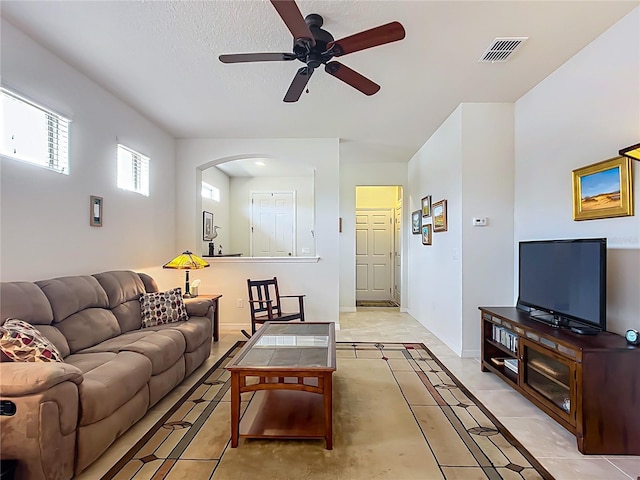 tiled living room with a textured ceiling and ceiling fan