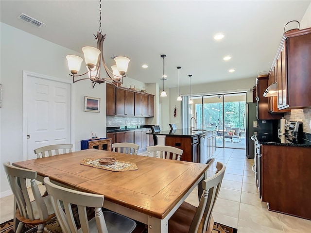 dining area with light tile patterned flooring, sink, and an inviting chandelier