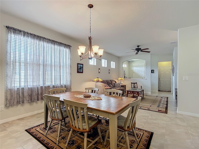 tiled dining room featuring ceiling fan with notable chandelier