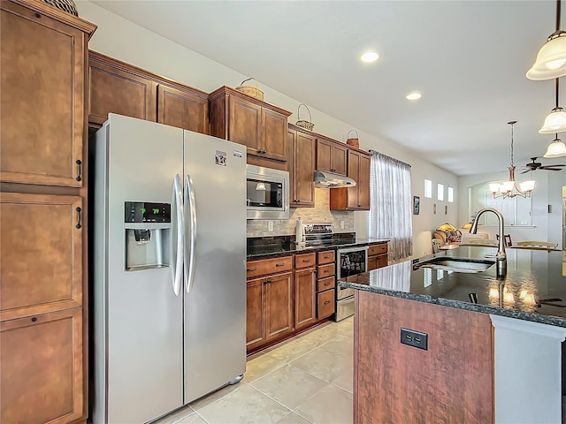 kitchen with sink, tasteful backsplash, dark stone counters, pendant lighting, and stainless steel appliances