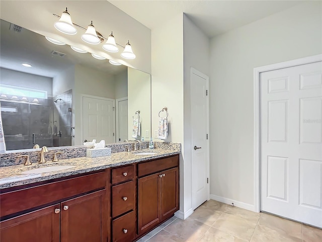 bathroom with a shower with door, vanity, and tile patterned flooring