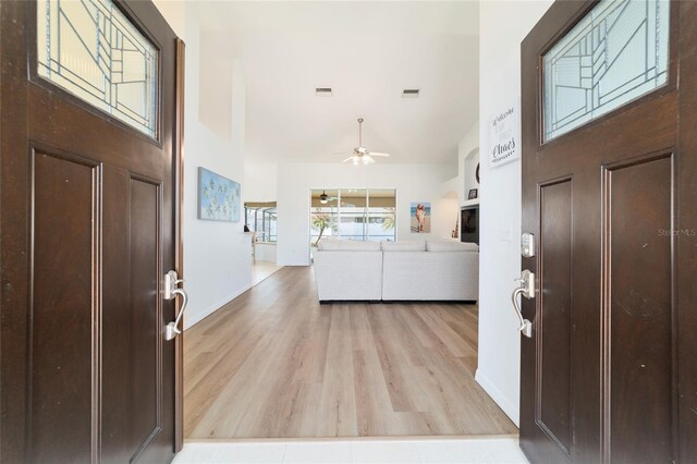 entryway with ceiling fan, high vaulted ceiling, and light wood-type flooring