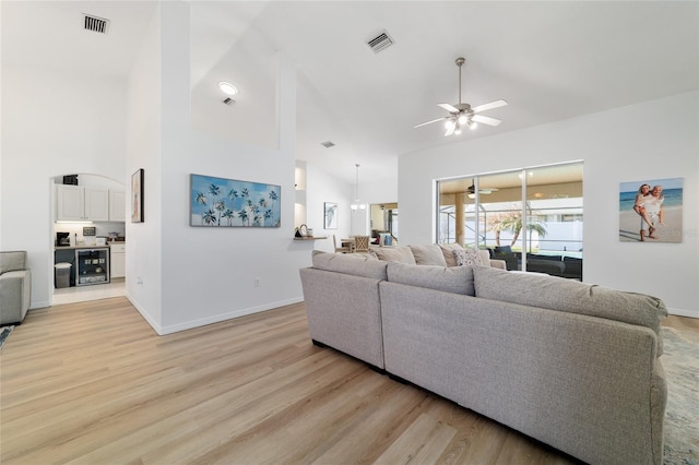 living room with ceiling fan, high vaulted ceiling, and light wood-type flooring