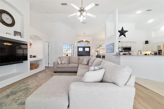 living room featuring ceiling fan, sink, high vaulted ceiling, and light hardwood / wood-style flooring