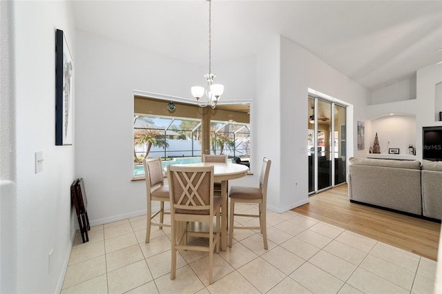 tiled dining room with lofted ceiling and a chandelier