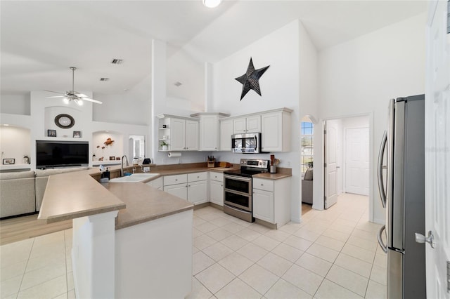 kitchen featuring light tile patterned flooring, appliances with stainless steel finishes, white cabinetry, sink, and kitchen peninsula