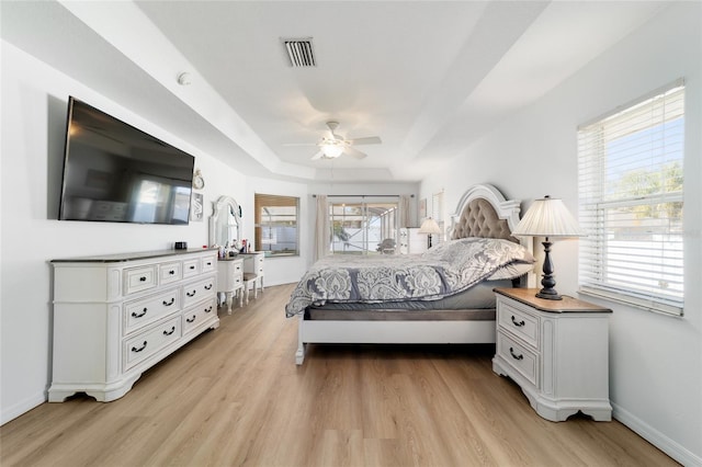 bedroom with a raised ceiling, ceiling fan, and light hardwood / wood-style flooring