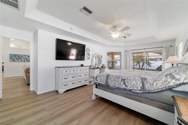 bedroom featuring a raised ceiling, ceiling fan, and light hardwood / wood-style floors