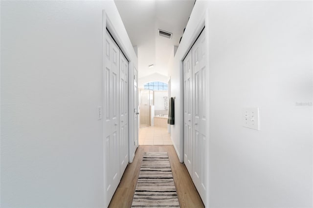 hallway featuring vaulted ceiling and light hardwood / wood-style floors