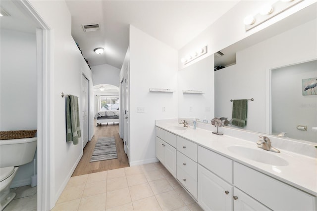 bathroom featuring lofted ceiling, tile patterned flooring, vanity, ceiling fan, and toilet