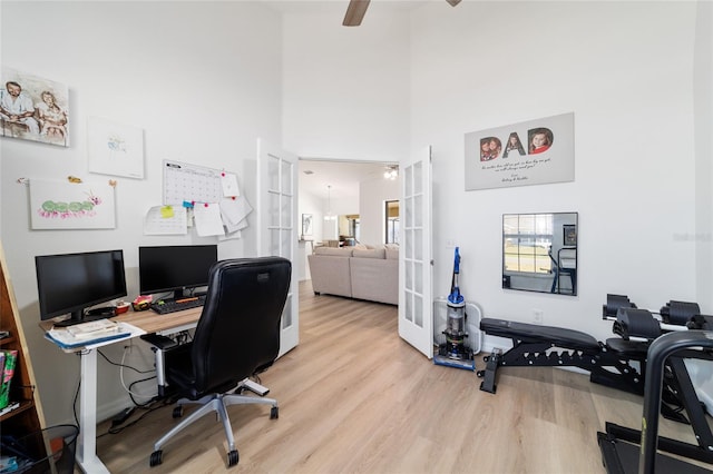 office space with a high ceiling, french doors, ceiling fan, and light wood-type flooring