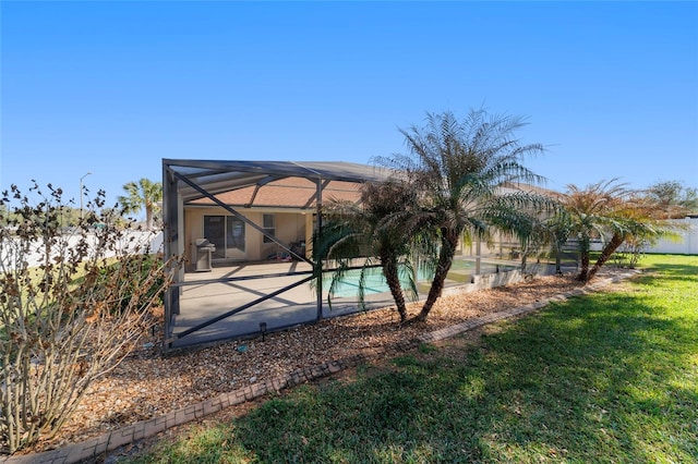 rear view of house featuring a yard and glass enclosure