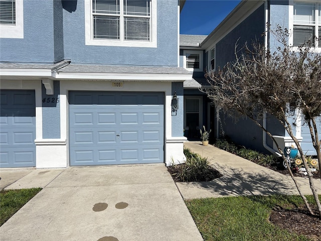 exterior space with concrete driveway, an attached garage, and stucco siding