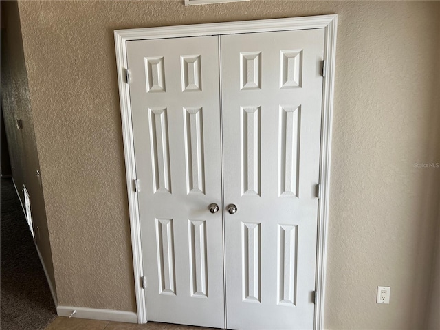 interior details featuring a textured wall and baseboards