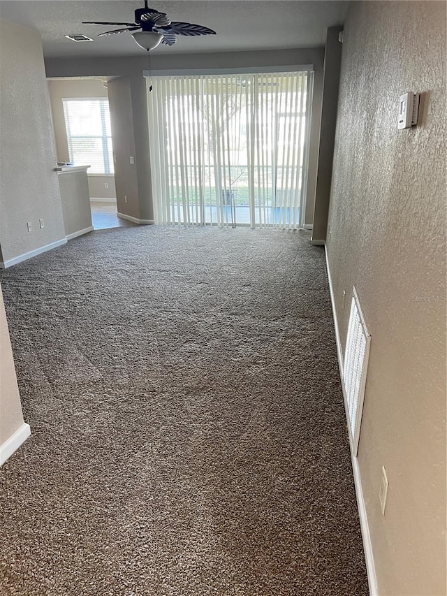 carpeted spare room with visible vents, a textured wall, and baseboards