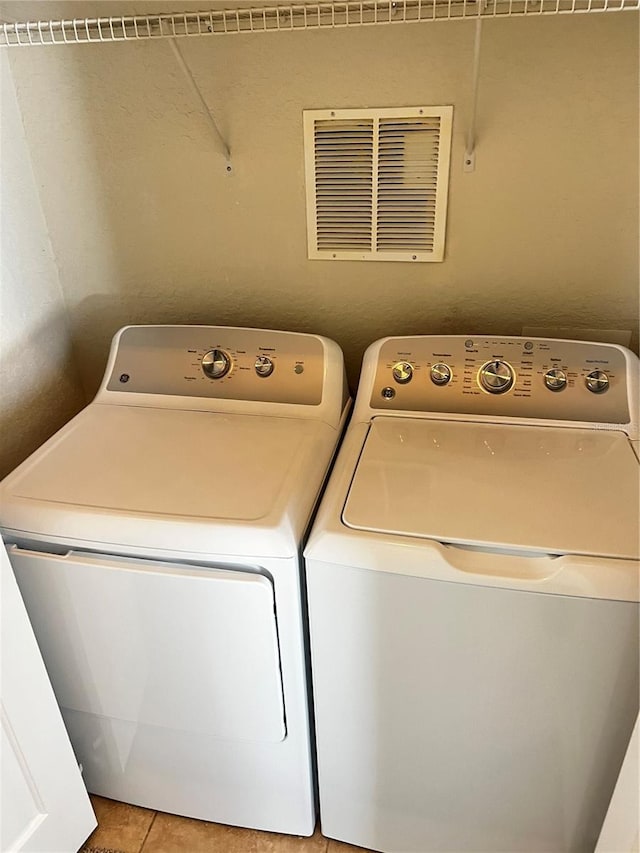 laundry room featuring laundry area, light tile patterned flooring, washing machine and clothes dryer, and visible vents