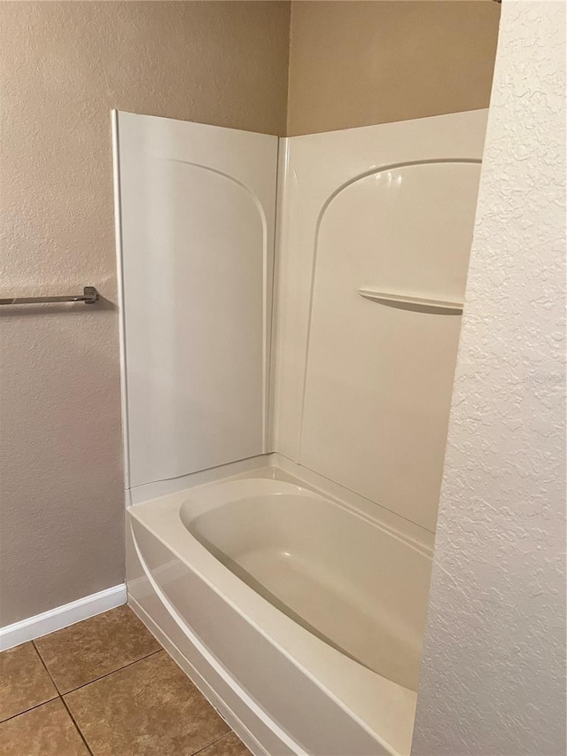 bathroom with shower / bath combination, tile patterned flooring, baseboards, and a textured wall