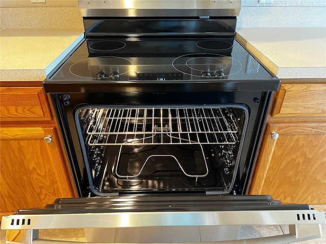 room details with brown cabinetry, light countertops, and range with electric stovetop