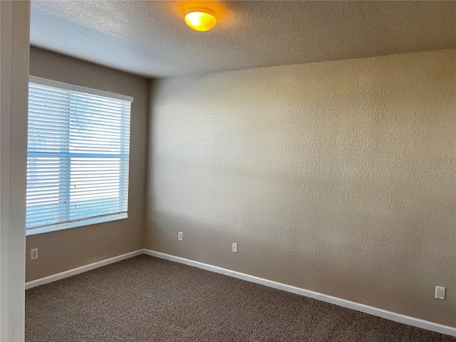 carpeted spare room with baseboards, a textured ceiling, and a textured wall