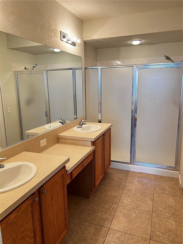 bathroom featuring a textured wall, tile patterned flooring, a textured ceiling, vanity, and a shower stall