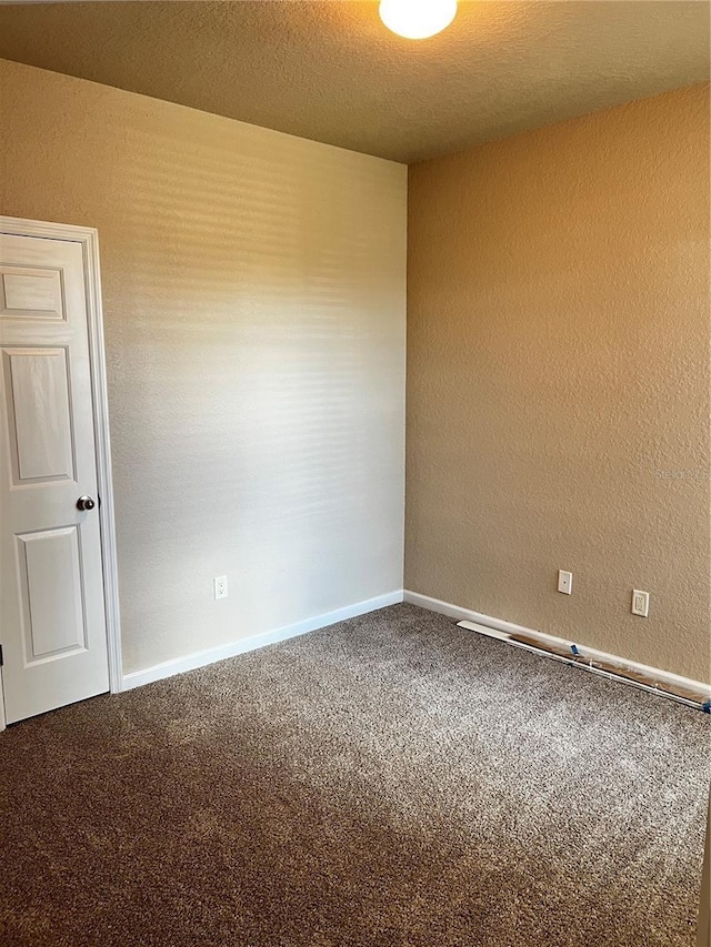 carpeted empty room with baseboards and a textured ceiling