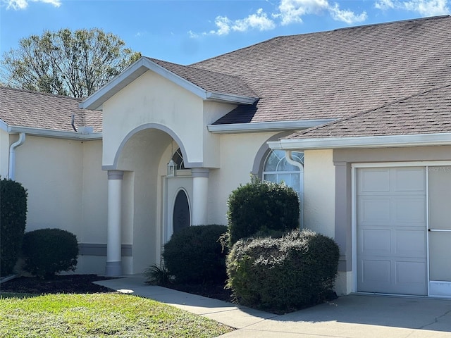 5500 NW 23rd Pl, Ocala, FL 34482 - view of exterior entry with roof with shingles, stucco siding, and a garage