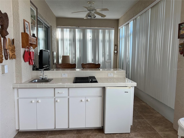 5500 NW 23rd Pl, Ocala, FL 34482 - kitchen featuring a ceiling fan, a peninsula, tile counters, stovetop with downdraft, and a sink