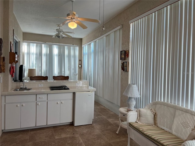 5500 NW 23rd Pl, Ocala, FL 34482 - kitchen featuring a ceiling fan, tile countertops, a sink, white cabinets, and a peninsula