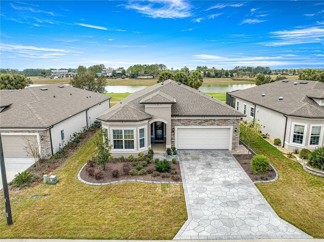 view of front of home with a garage, a front lawn, and a water view