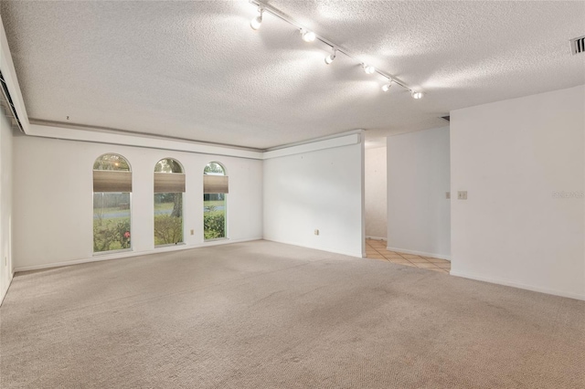 empty room with track lighting, light colored carpet, and a textured ceiling