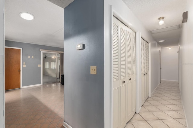 hallway featuring light tile patterned floors and a textured ceiling