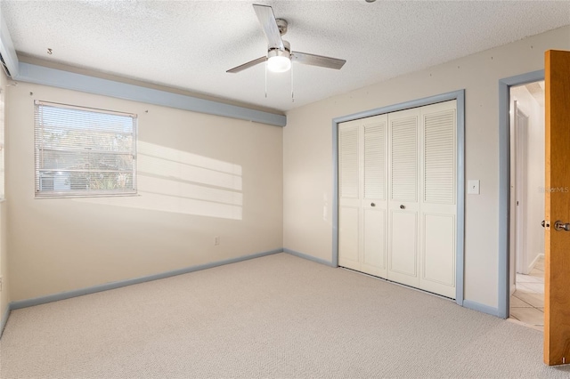 unfurnished bedroom featuring ceiling fan, light colored carpet, a closet, and a textured ceiling